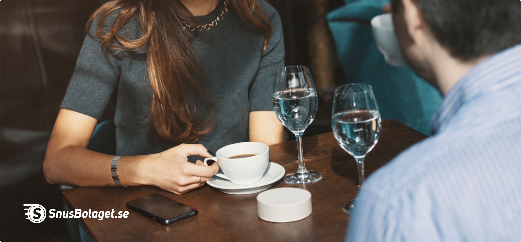 Kaffe och snus på ett café bord, där två personer sitter mitt emot varandra