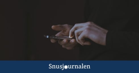 Hand som skriver med mobilen med mörk bakgrund - snus från svarta marknaden